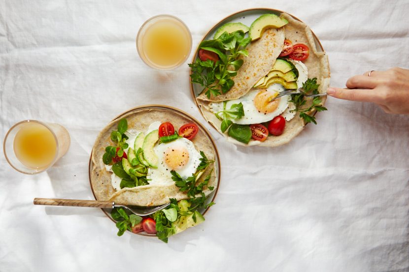 Rye flour pancakes with avocado, cream cheese, cherry tomatoes and egg